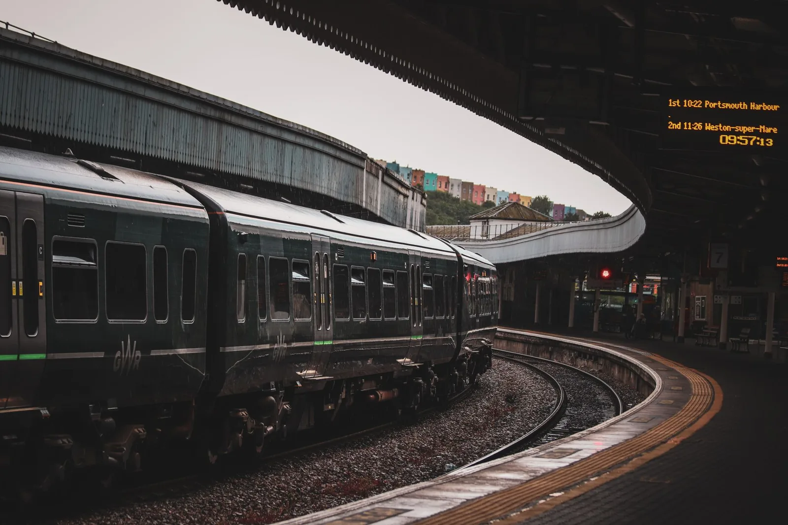 Train waiting at a curved platform under a station canopy
